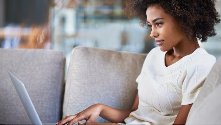 image of a woman looking at a laptop on a couch